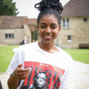 Black female youth smiles and reaches out to the camera